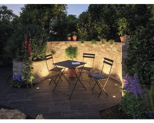 Garten mit Steinterrasse, Steinmauer, Tisch, Stühlen und Pflanzen