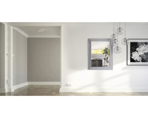 Dekorativer Spiegel, Hängeleuchte und gerahmtes Bild an einer Wand in einem Wohnzimmer