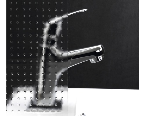 Dekorglas mit quadratischem Muster vor einem Wasserhahn