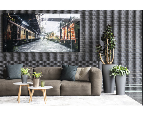 Wohnzimmer mit Sofa, Couchtischen, Topfpflanzen und einem gerahmten Bild von Zugwaggons