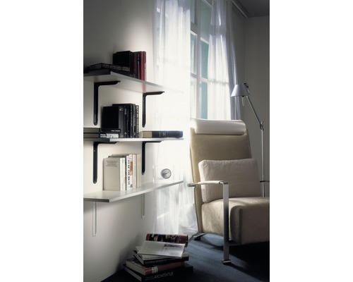 Wohnzimmer mit Bücherregal an der Wand und Sessel neben einem Fenster