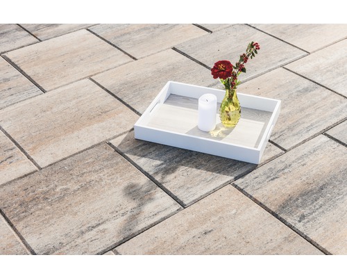 Verbundsteine auf Terrasse mit Tablett, Blumenvase und Kerze