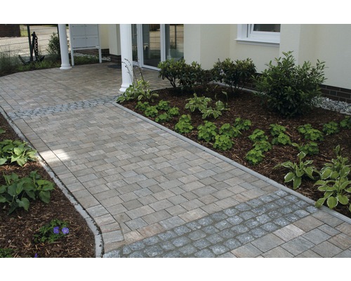 Gepflasterter Weg zu einem Haus mit bepflanzten Beeten