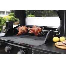 Gasgrill mit zwei Brathähnchen auf einem Drehspieß und Zitronen auf einer Holzplatte