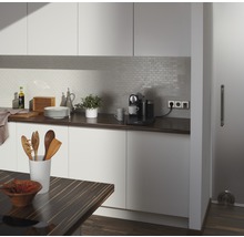 Helle Küche mit Arbeitsplatte, Küchenutensilien, Kaffeemaschine und Fliesenrückwand