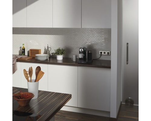 Helle Küche mit Arbeitsplatte, Küchenutensilien, Kaffeemaschine und Fliesenrückwand