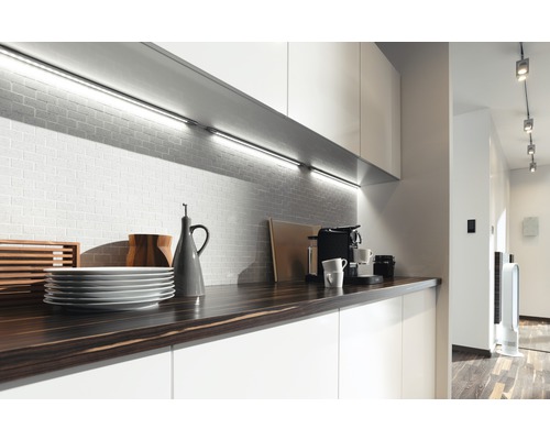 Moderne Küche mit Arbeitsplatte, Geschirr, Kaffeemaschine und Unterbauleuchten