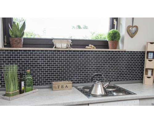 Küchenszene mit schwarzem Fliesenspiegel, Arbeitsfläche und Dekorationselementen.