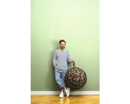 Mann lehnt an Wand und hält einen runden Sitzsack mit Tarnmuster