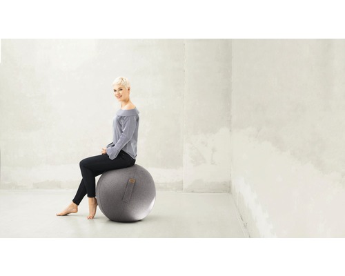 Frau sitzt auf einem Gymnastikball im Büro.