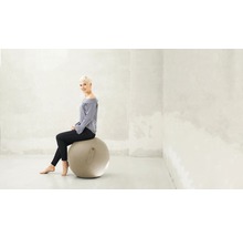 Frau sitzt auf einem Gymnastikball in einem hellen Raum.