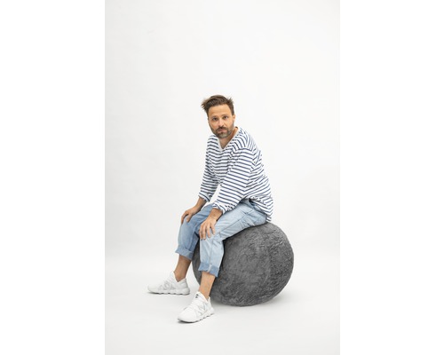 Mann sitzt auf einem grauen Sitzball