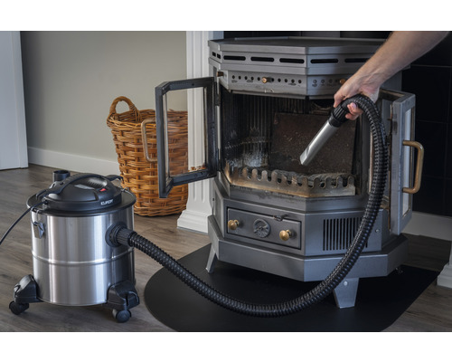 Kaminofen wird mit einem Aschesauger gereinigt.