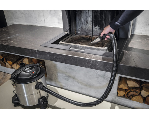 Eine Person reinigt einen Kamin mit einem Aschesauger.