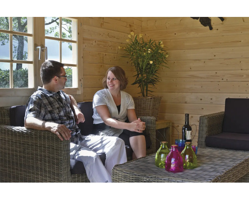 Wohnszene mit Paar auf Rattansofa in Holzhütte