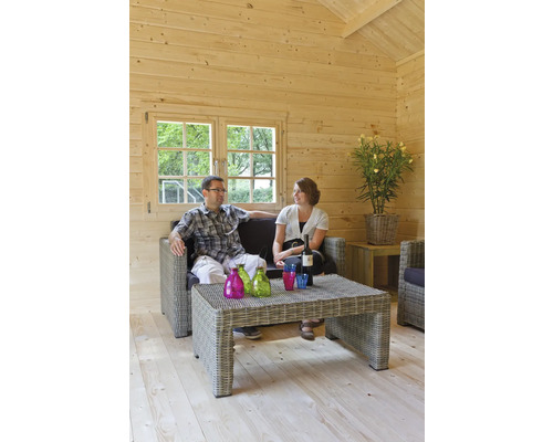 Helles Holzhäuschen mit einem Paar auf einem Rattansofa mit Tisch, Flaschen und Gläsern