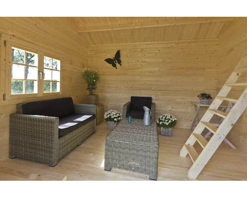 Innenraum eines Holzhauses mit Sofa, Sessel, Tisch und Leiter