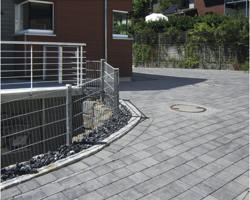 Außenbereich mit Pflastersteinen, Metallzaun und Haus
