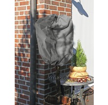 Pflanze mit Winterschutzhaube auf einem Gartentisch vor einer Backsteinmauer