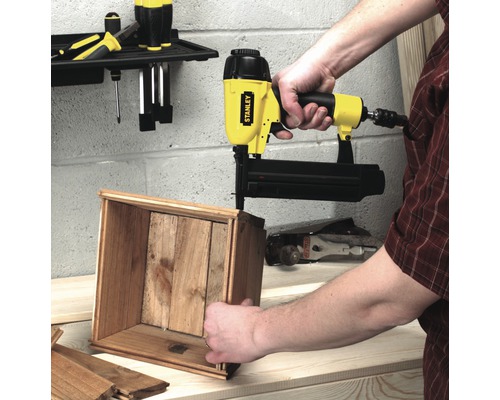 Eine Person verwendet einen Stanley Nagel-Tacker, um eine Holzkiste zusammenzufügen.