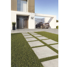 Moderne Hausansicht mit Betonplattenweg durch Rasenfläche und einem Auto im Carport