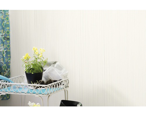 Helle Wand mit senkrechter Struktur neben einem Tisch mit Blumen