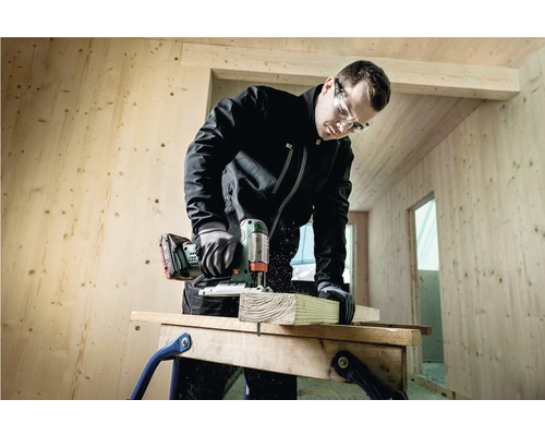 Handwerker sägt Holz mit einer Stichsäge in einem Holzhaus.