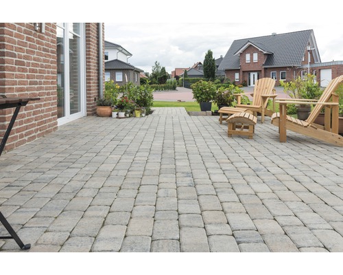 Terrasse mit Pflastersteinen, Gartenmöbeln und Pflanzen