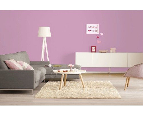 Helles Wohnzimmer mit Sofa, Tisch und Dekoration vor lila Wand