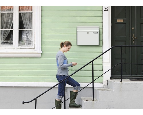 Eine Frau geht die Treppe zu einem Haus mit einem Briefkasten hinauf.