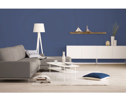 Wohnzimmer mit Sofa, Lampe, Regal und Dekoration vor einer farbigen Wand