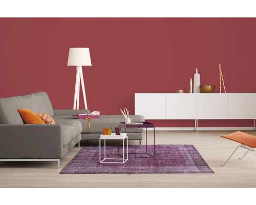 Wohnzimmer mit Sofa, Teppich, Stehlampe und Sideboard vor einer farbigen Wand