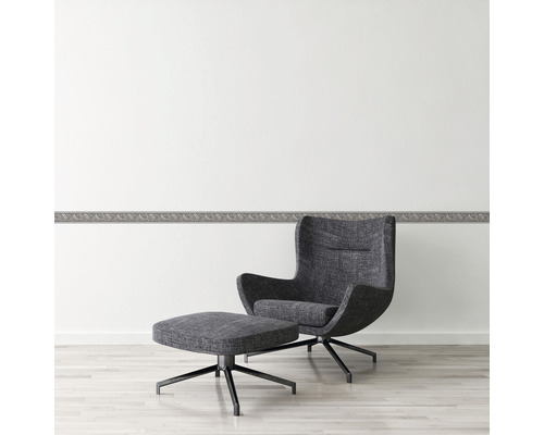 Wohnraum mit Zierbordüre und Sessel mit Fußhocker