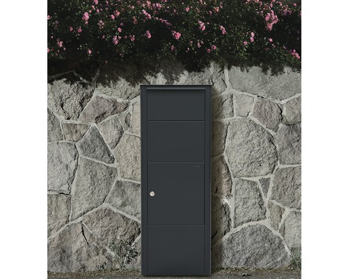 Freistehender Briefkasten vor einer Steinmauer mit blühenden Rosen