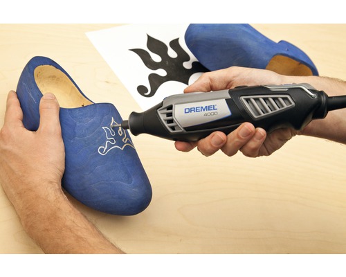 Dremel Logo. Eine Person verwendet einen Dremel 4000 Multifunktionsschleifer, um ein Muster in einen Holzschuh zu schnitzen.