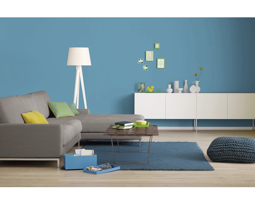 Modernes Wohnzimmer mit Sofa, Couchtisch, Teppich und dekorativen Elementen vor einer farbigen Wand
