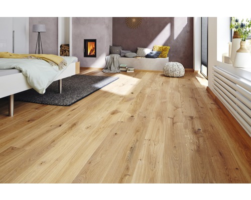 Heller Holzboden in einem Schlafzimmer mit Bett und Kamin