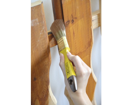 Eine Person streicht Holz mit einem Pinsel von Bondex.
