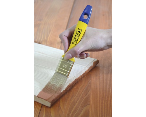 Hand streicht Holzbrett mit Bondex Pinsel