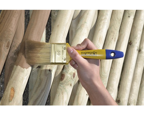 Eine Person streicht mit einem Pinsel eine Holzwand. Bondex Logo ist sichtbar.