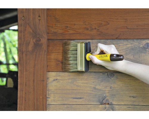 Eine Person streicht Holz mit einem Flächenstreicher von Bondex.