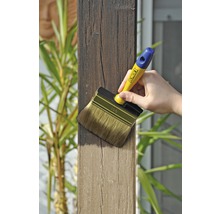 Eine Person streicht eine Holzoberfläche mit einem Pinsel der Marke Bondex.