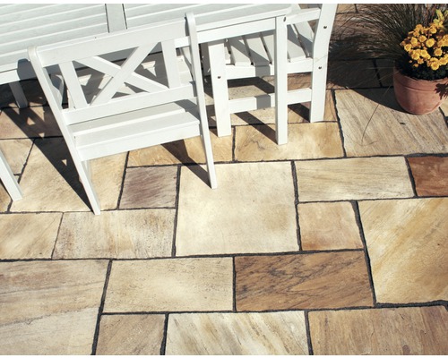 Verlegtes Natursteinpflaster im Außenbereich mit Sitzgruppe und Blumentopf.