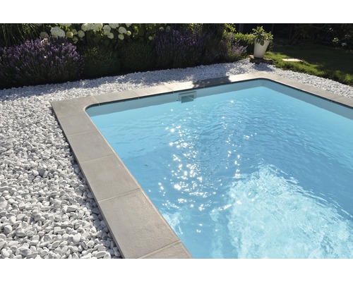 Swimmingpool mit grauen Beckenrandsteinen und weißen Zierkieseln im Garten