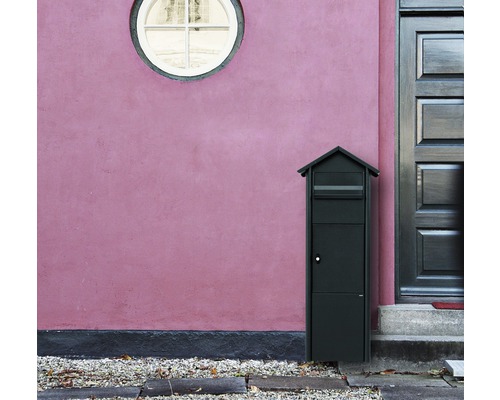 Freistehender Briefkasten vor einer Hauswand mit Tür und Fenster