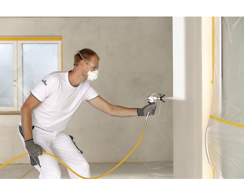 Handwerker verwendet Farbspritzgerät zum Streichen einer Wand