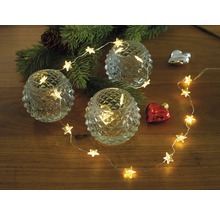 Dekorative Anordnung mit Teelichthaltern, Lichterkette in Sternform und Weihnachtsschmuck auf einem Tisch.