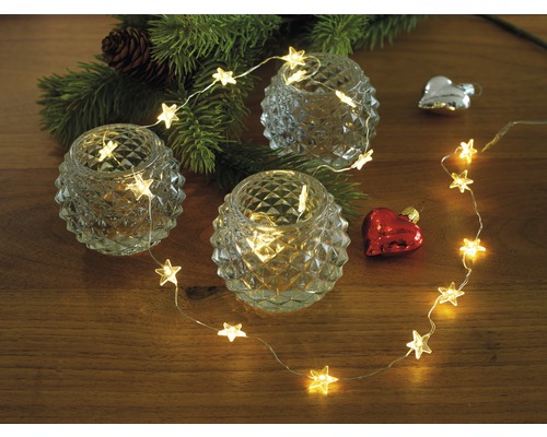 Dekolichterkette Konstsmide Sterne Lichtfarbe warmweiß 2,1 m + Zuleitung 50 cm 40 LEDs batteriebetrieben Dekorative Anordnung mit Teelichthaltern, Lichterkette in Sternform und Weihnachtsschmuck auf einem Tisch.