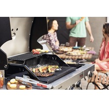 Edelstahl Grill mit Grillgut und Personen im Hintergrund