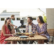 Gruppe von Freunden grillt und isst gemeinsam im Freien.